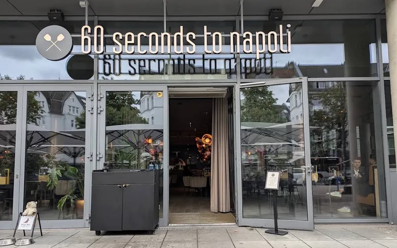 Eingang von 60 seconds to Napoli in der Hammer Straße mit Leuchtschrift über den geöffneten Glastüren.