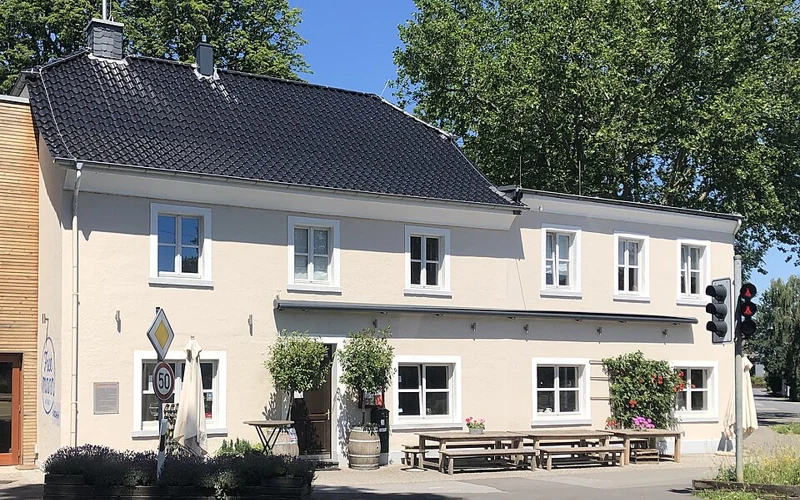 Fassade des Landhaus Freemann in Düsseldorf-Kalkum mit Eingang und Sitzbänken an der Kalkumer Schlossallee.