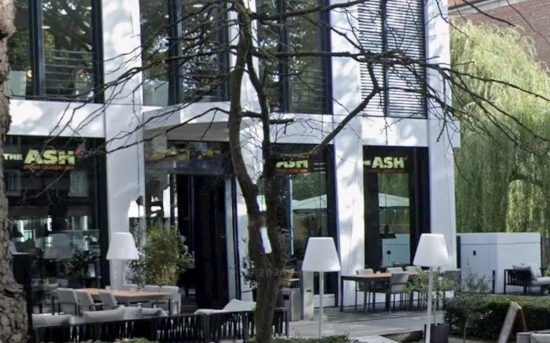 Gebäude von THE ASH in Düsseldorf mit Schriftzug, Eingang und Terrasse.